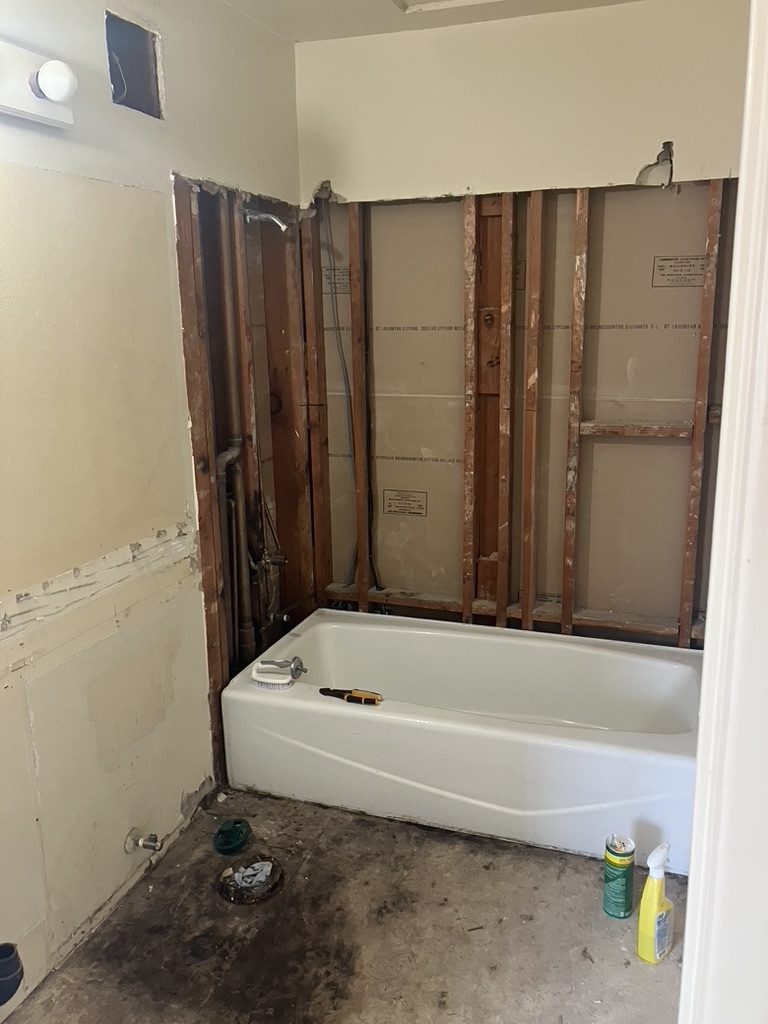 Bathroom before remodel — tub set, walls open to studs