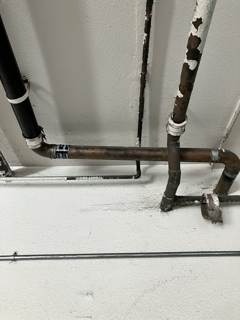 Leaking copper drain line in parking garage before repair